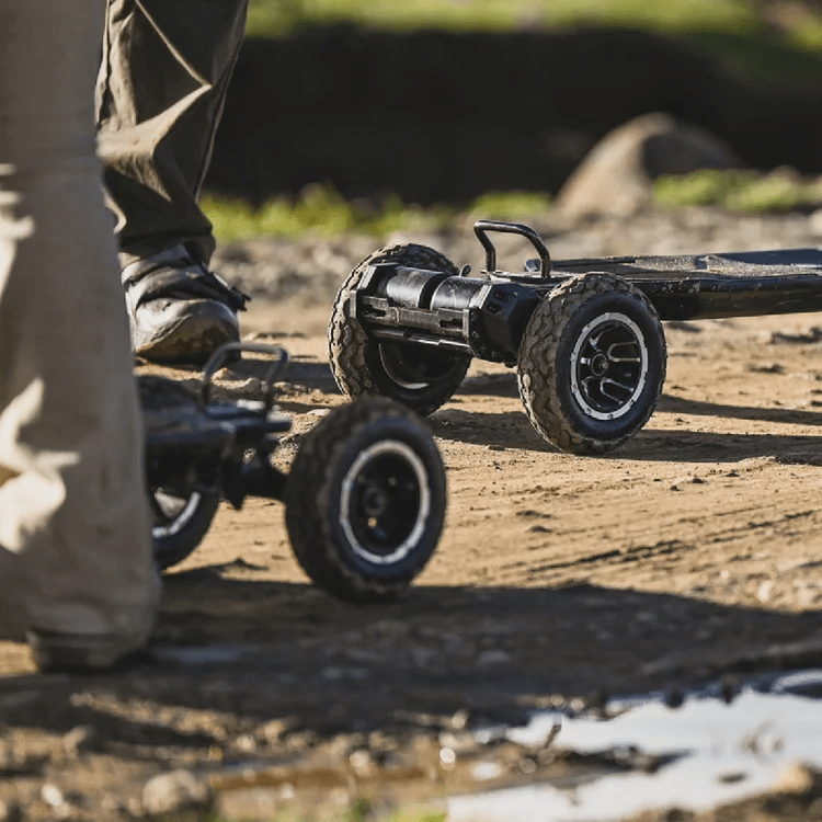 two people with exway atlas pro 4wd electric skateboards outside on a muddy road